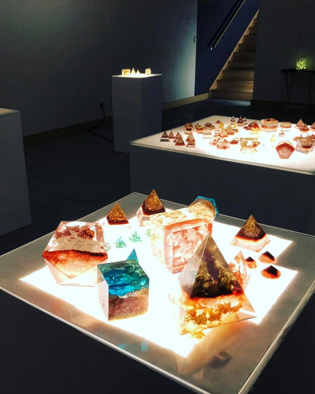 Illuminated sculptural artworks displayed in a dark gallery space